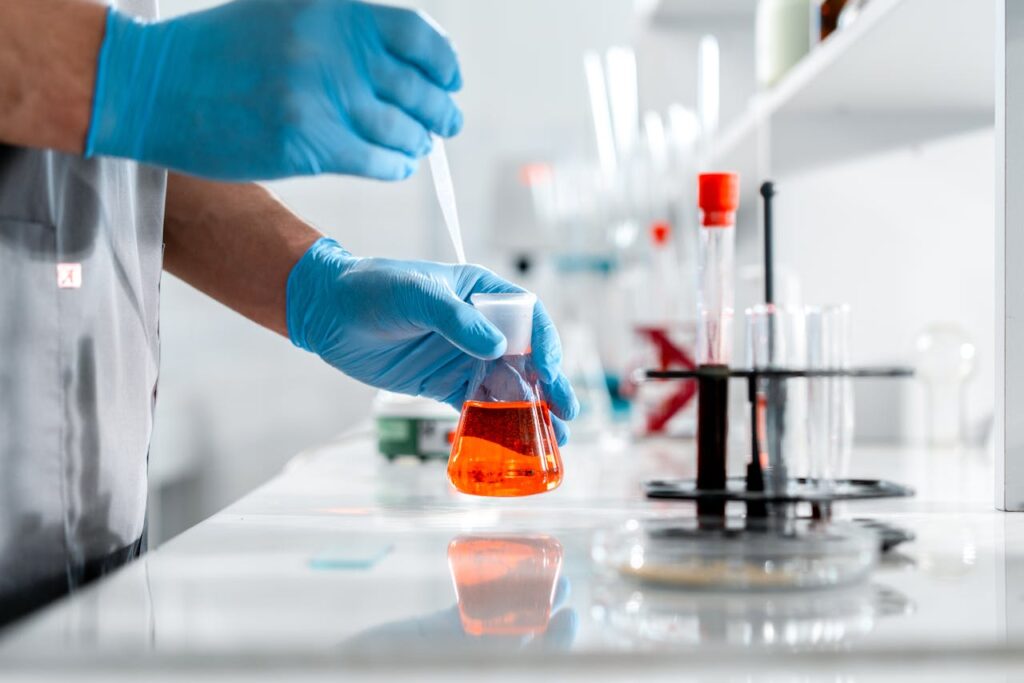 Scientist carefully working with Erlenmeyer flask and pipette in a laboratory setting.